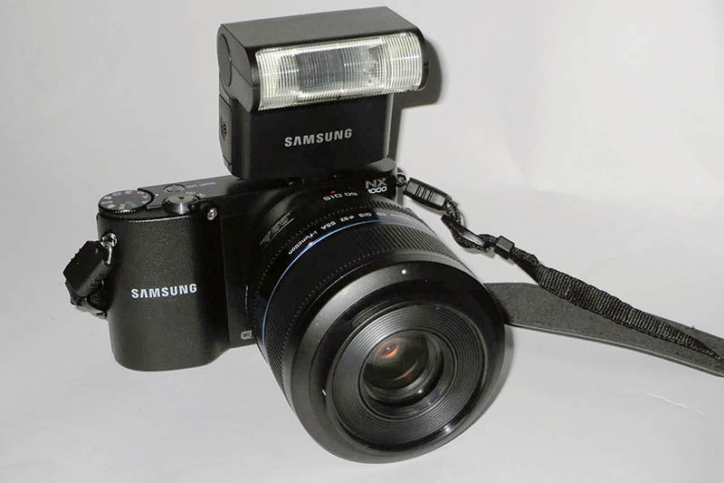 Samsung NX1000 mit Systmeblitz und
                      60-mm-Makroobjektiv